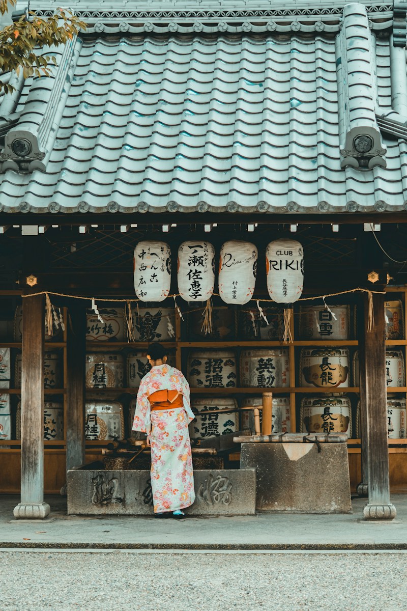 woman wearing orange and white kimono dress standing near the house