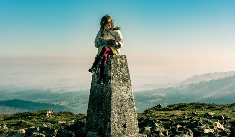 a woman sitting on top of a stone pillar