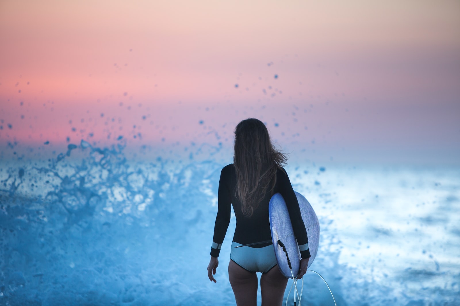 woman in black long sleeve shirt and white shorts standing on blue water during sunset